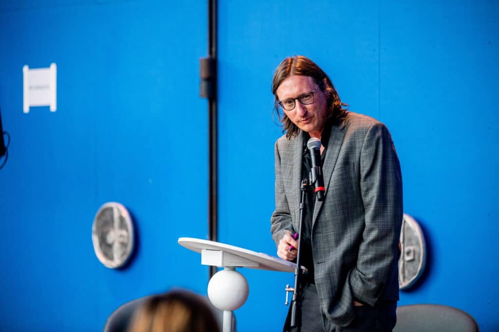 Photo of poet Todd Robinson standing at a podium.