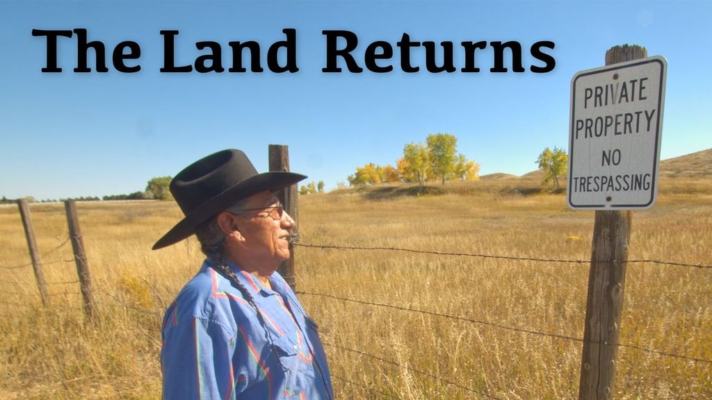 A man in braids and a brimmed hat wearing denim shirt and jeans looks at a sign posted on a barbed wire fence that says "private property no tresspassing". The landscape shows grassland with trees and a hill and the background.